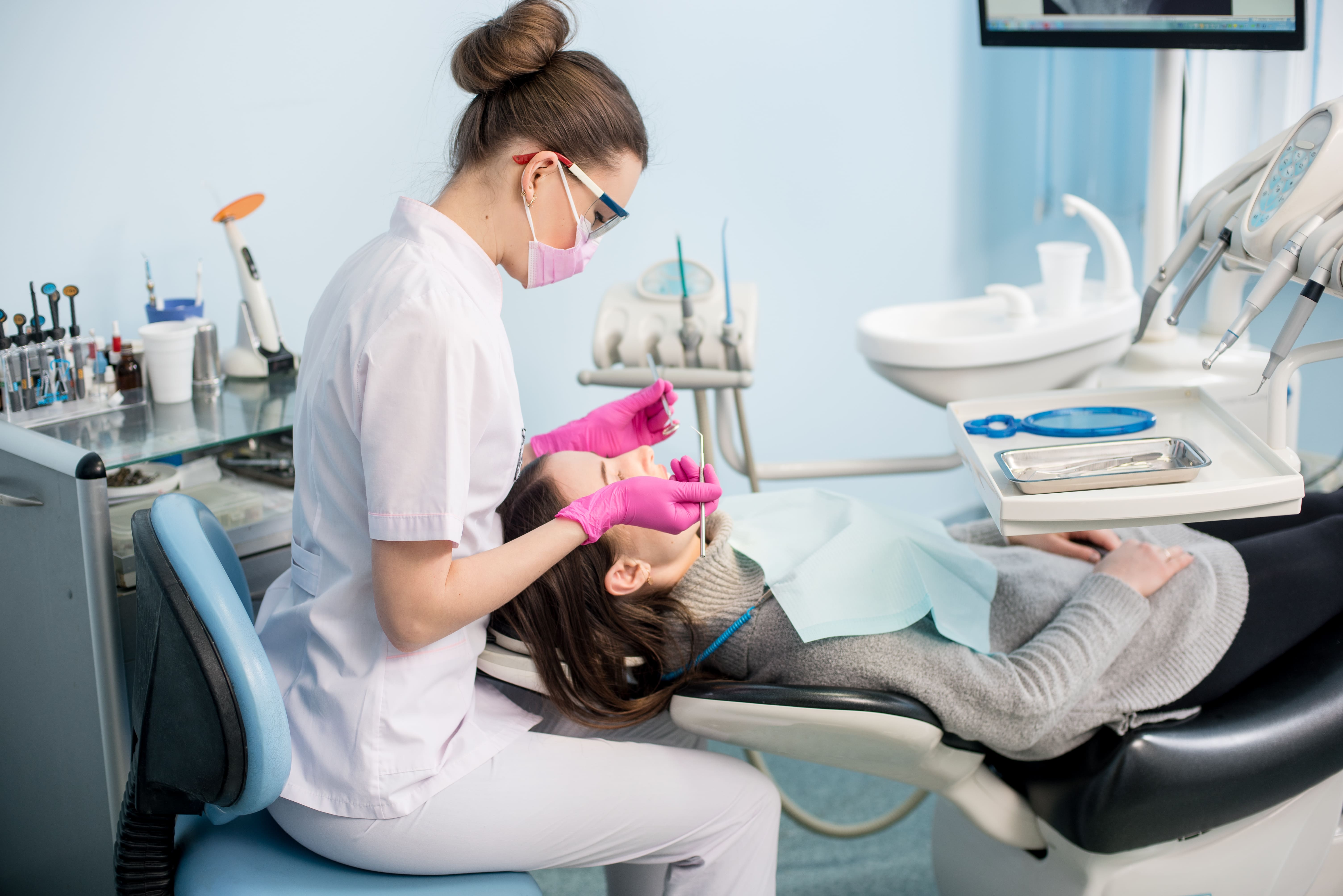 Female dentist with dental tools - mirror and probe checking up patient teeth at dental clinic office-1