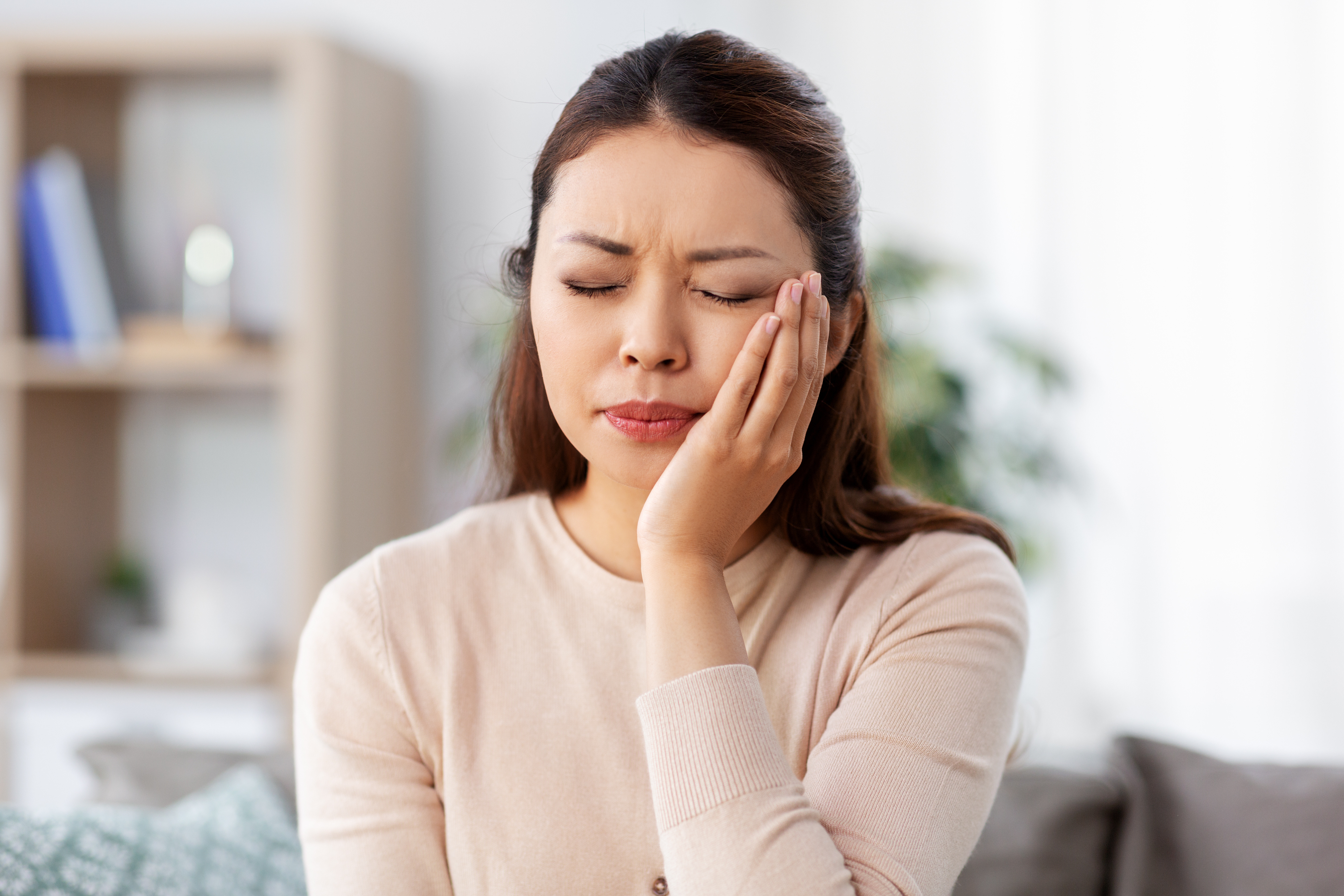 healthcare, dental health and problem concept - unhappy asian woman suffering from toothache at home